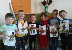 Uczniowie klasy 1b prezentujący Misie Uszatki wykonane z liści