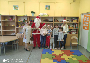 Pamiątkowe zdjęcie z Mikołajem i Śnieżynką dzieci z klasy 2b w świetlicy szkolnej wraz z wychowawczynią świetlicy