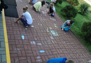Dzieci w czasie pracy, malują kropkowe obrazy na chodniku