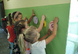 Dziewczynki przyklejają kropki na ścianie korytarza