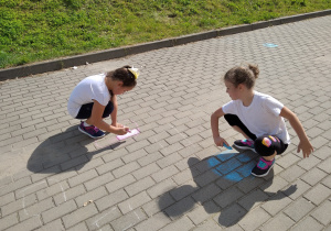 Dziewczynki malujące kropki przed wejściem do szkoły
