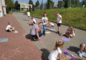 Dzieci oraz wychowawczyni klasy malujący kropki przed wejściem do szkoły