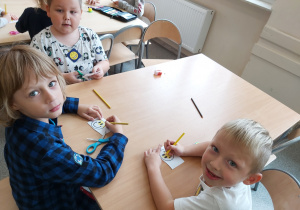 Dzieci z oddziału przedszkolnego przygotowują żółte znaczki z uśmiechniętą buzią