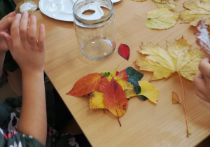 Dzieci starannie przyklejały liście do słoików