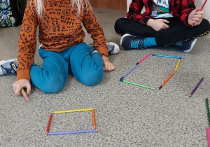 Dzieci układają figury geometryczne z kredek
