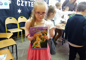 Ania dumnie pokazuje swoją pierwszą wypożyczoną książkę